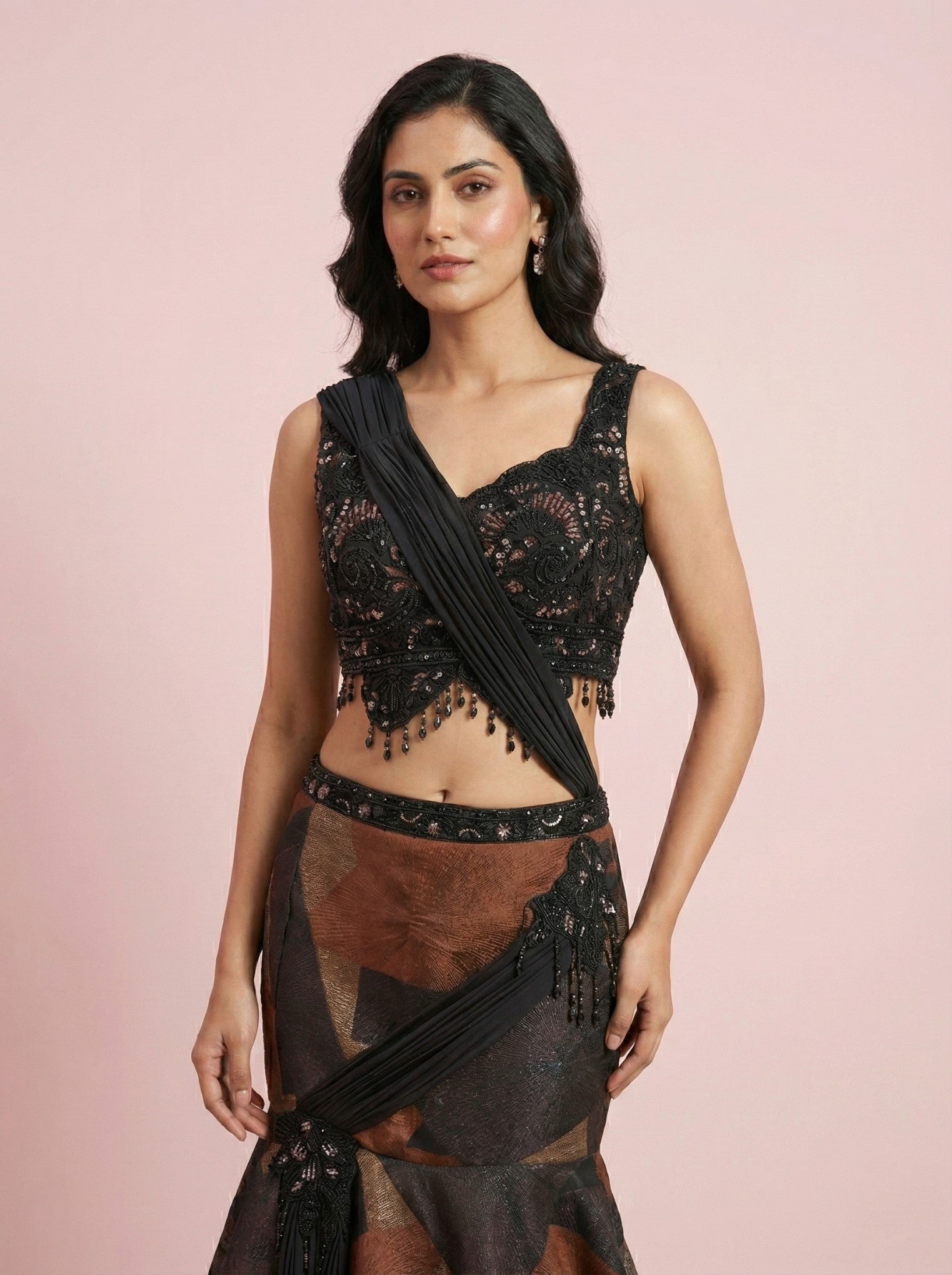 Woman wearing a black drape lehenga on a pink background
