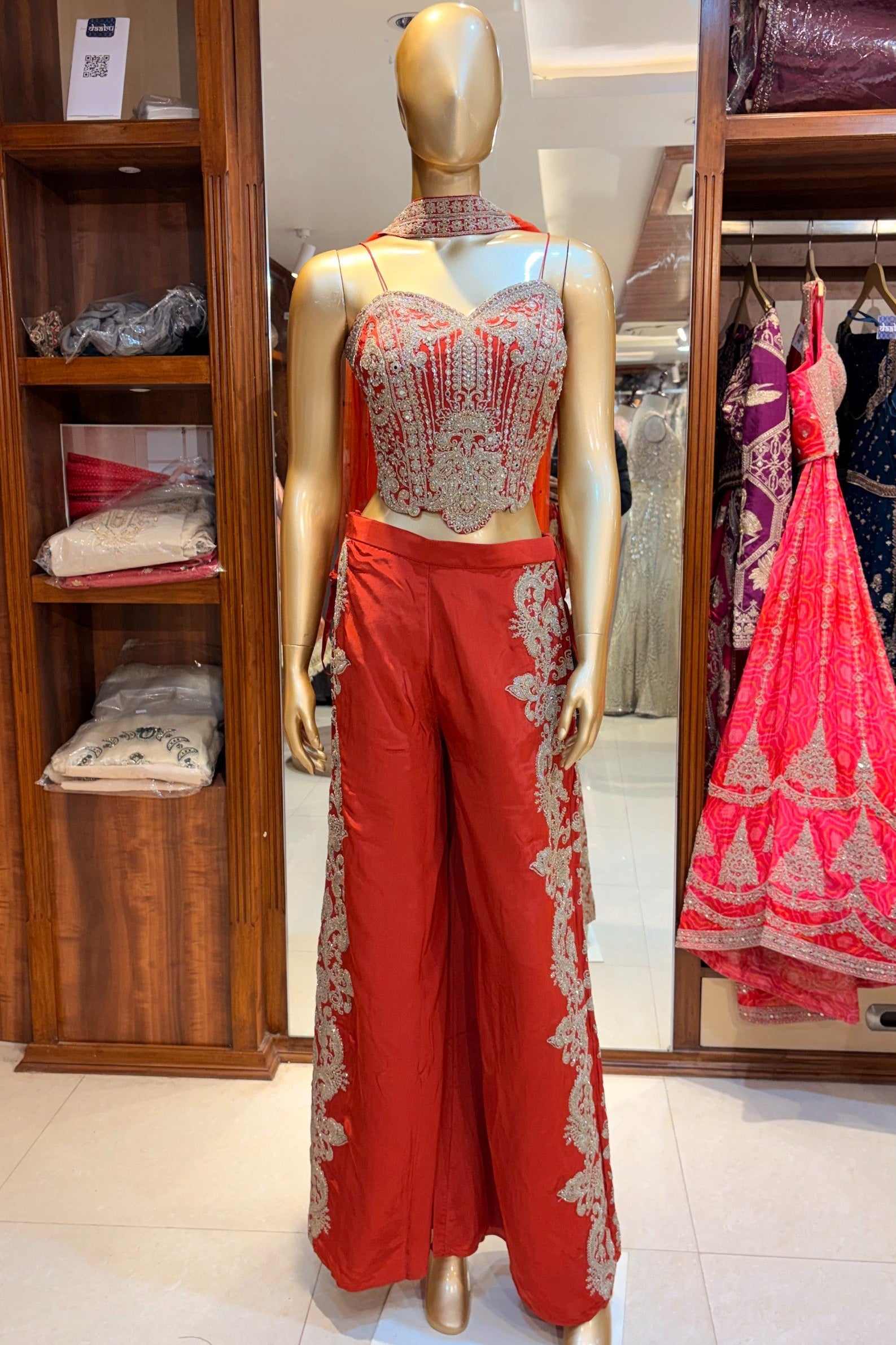 Mannequin wearing a RUST ORANGE outfit with gold embroidery in a store setting