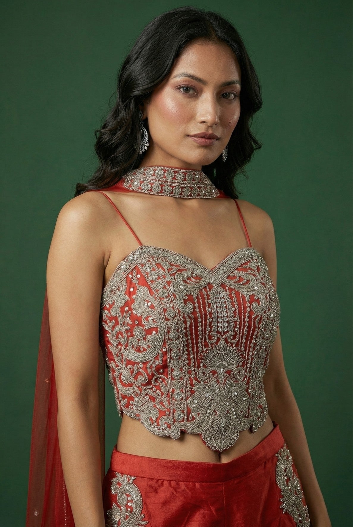 Woman wearing a ORANGE and silver traditional outfit against a green background